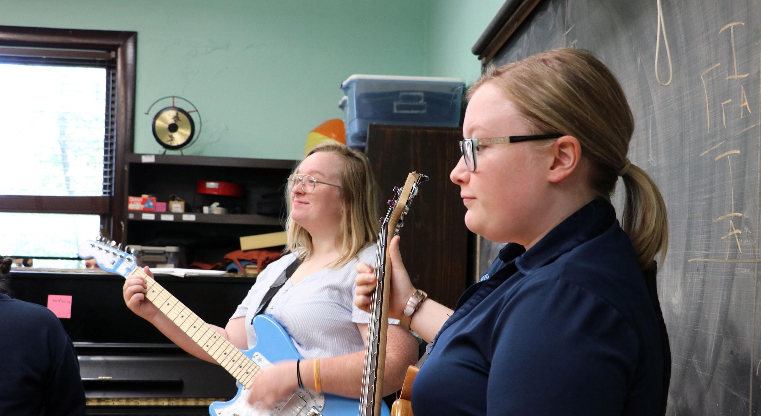 Two students playing guitar