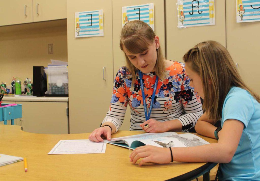 A teacher helps a young student learn to read.